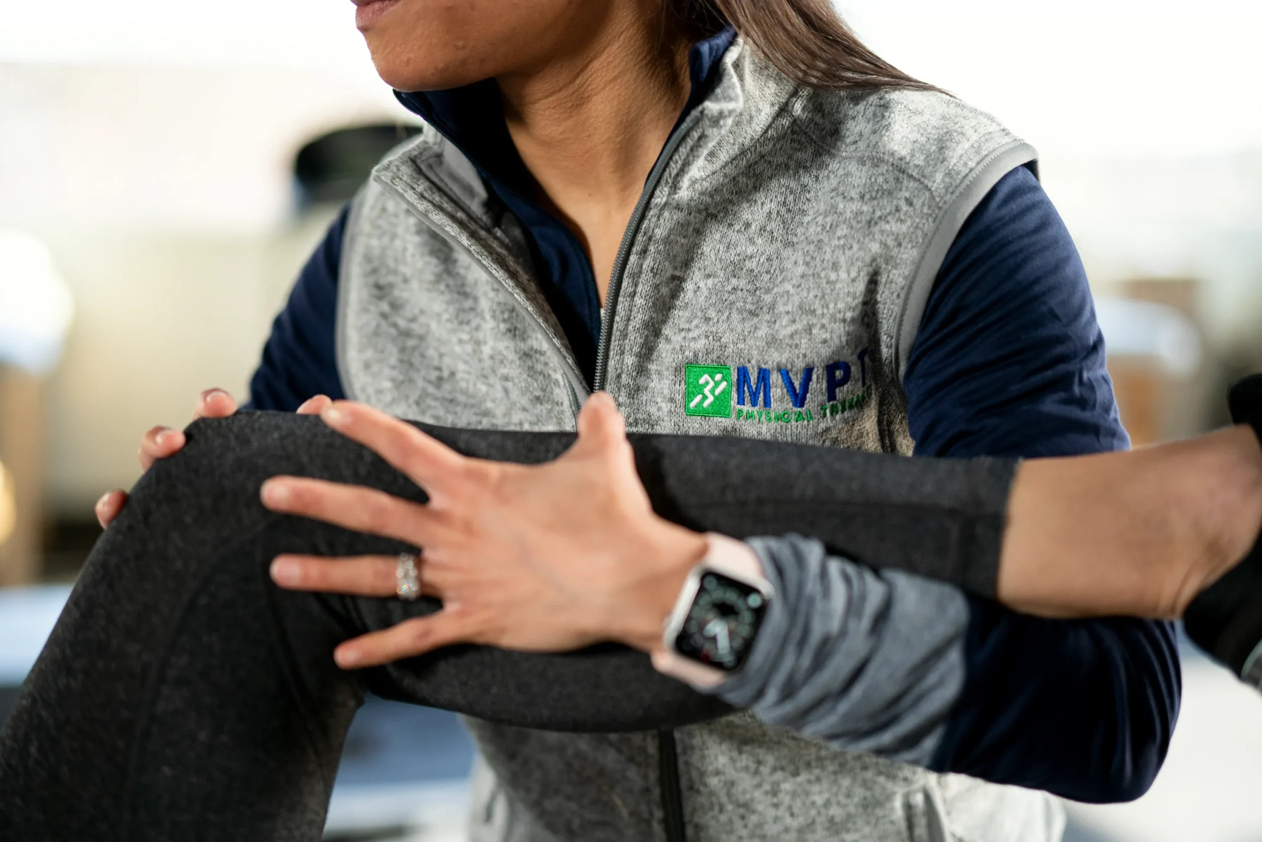 A patient receives a knee stretch from a physical therapist, highlighting the partnership in physical therapy and surgery for recovery.