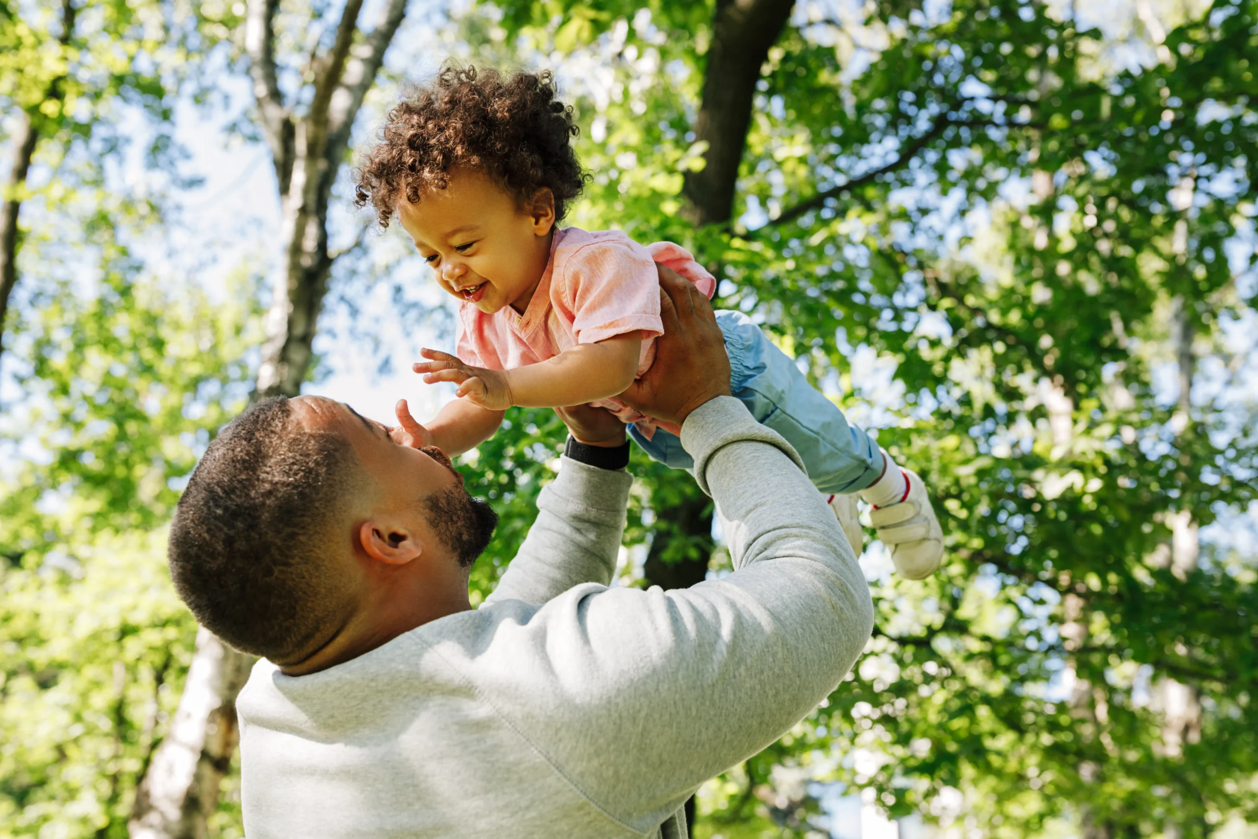 Father carrying child playing outside and laughing. 